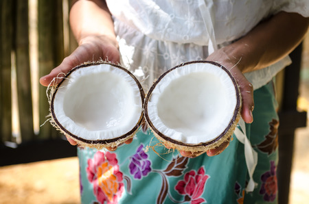 a local thai lady is showing coconut after breaking for making coconut milk.の写真素材