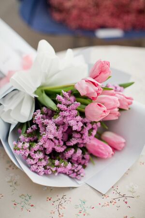 Bouquet with pink tulips and small pink flowers in a white wrapping paper with a ribbonの写真素材