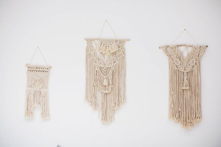 Three macrame wall decorations are hanging on a white wallの写真素材