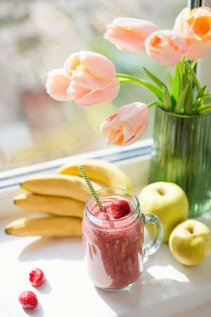 Healthy diet smoothie with strawberry, banana and apples in glass mason jar. Smoothie and bouquet of...