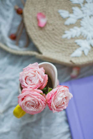 Small bouquet of pink roses and straw bag with embroidery on white tissue. Top viewの写真素材