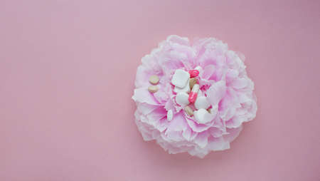 Allergy concept, flower and pills. Pink peony and assorted pills on a pink backgroundの写真素材