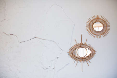 Vintage rattan mirrors on white textured wall. Eye mirror and round mirror with frame of eco strawsの写真素材