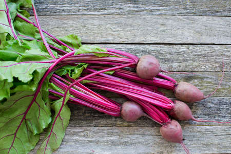 Fresh organic beet with leaves on rustic wooden background. Top view, copy space.