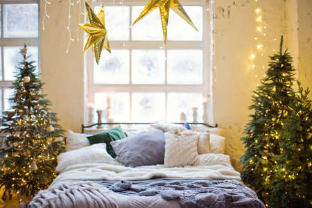 Christmas loft bedroom with big windows, Christmas decorations, Christmas trees and lights. Loft boho interior with Christmas decorの写真素材