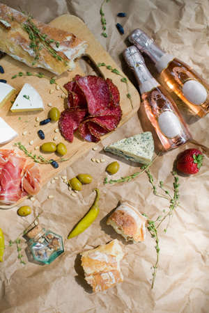 Italian antipasto, wooden cutting board with prosciutto, ham, cheese, green pepper and olives on a...