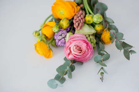 Beautiful bouquet with orange and pink ranunculus flowers, eucalyptus and hyacinth in a green vase...
