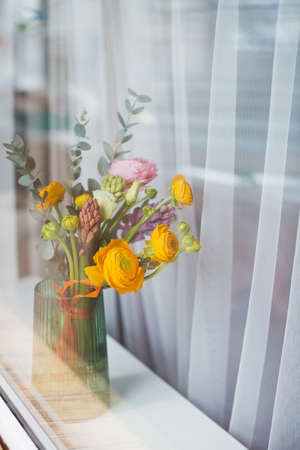 Beautiful bouquet with orange and pink ranunculus flowers, eucalyptus and hyacinth in a green vase...