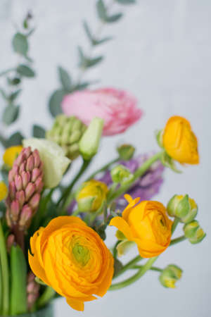 Beautiful bouquet with orange and pink ranunculus flowers, eucalyptus and hyacinth in a green vase on a white backgroundの写真素材