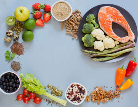 Balanced diet food frame background. Fresh vegatables, fruits, cereals, seeds and nuts on a blue background. Food frame with copy spaceの写真素材