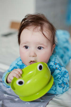 Little baby boy play with his green plastic plate