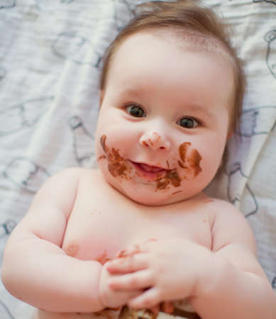 Cute baby boy eating chocolate paste. Dirty face of chocolateの写真素材
