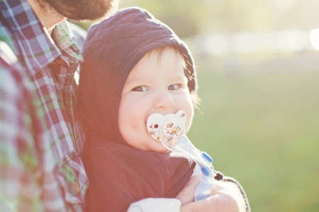 Little baby with pacifier with daddy walking in the park