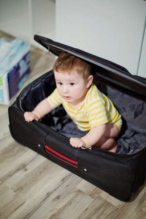 Little boy inside the black suitcase. Waiting for vacationの写真素材