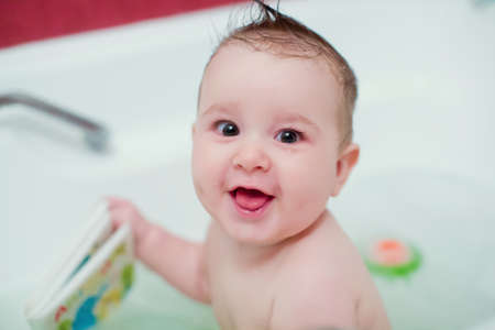 Little boy playing at bathtub in a water with bath foam