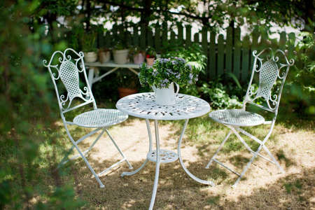 White metal garden table and chairs. Outdoor cozy garden furniture.