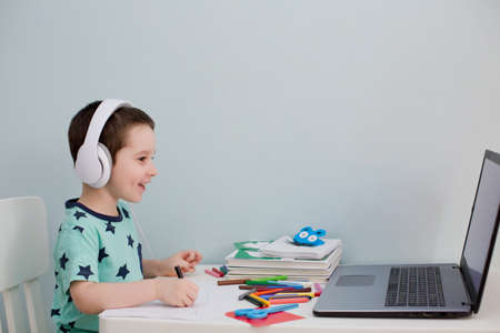 Distance online education concept. Little caucasian boy in headphones have video call studies online...