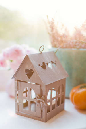 Vintage metal house lantern with burning candle, flowers in vases and orange persimmon on a windowsillの写真素材