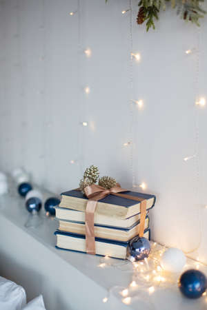 Stack books with ribbon, Christmas balls and Christmas lights near white wallの写真素材