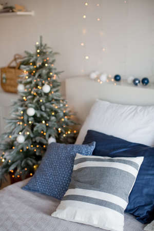 Light Christmas bedroom with Christmas tree, Christmas lights, pillows and other festive decorationsの写真素材