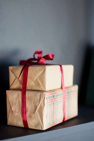 Brown craft boxes with red ribbon on a background of black wallの写真素材