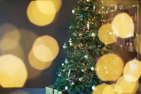 Christmas tree with golden decorations and lights in dark interiorの写真素材