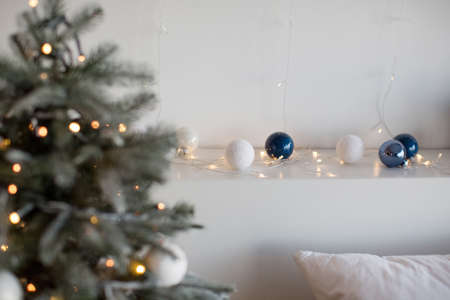 Christmas tree and white and blue Christmas balls with Christmas lights on a white background