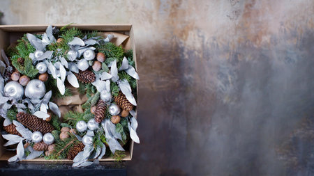 Christmas banner with wreath with natural elements, silver apples and leaves. Green and silver Christmas wreath on a brown grunge backgroundの写真素材