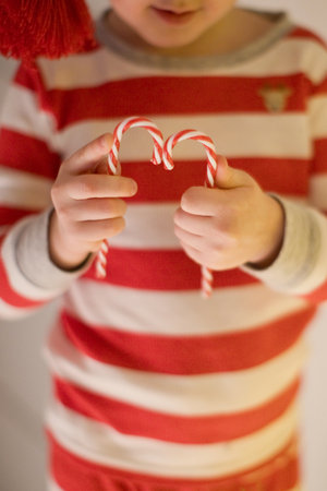 Child in striped pajamas hold candy canesの写真素材