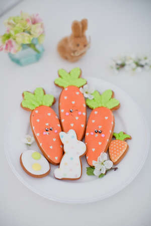 Easter glazed cookies and white spring flower on a white plate. Carrot, bunny and egg shaped...