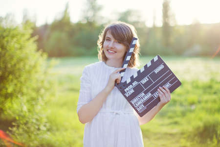 Beautiful caucasian woman holds clapper board at sunset lightの写真素材