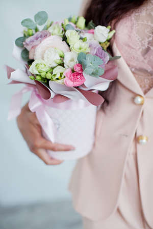 Woman in pink clothes holds box with beautiful flowers