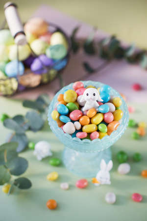 Pastel Easter decorations with bunny, colorful eggs candy on a light colorful backgroundの写真素材