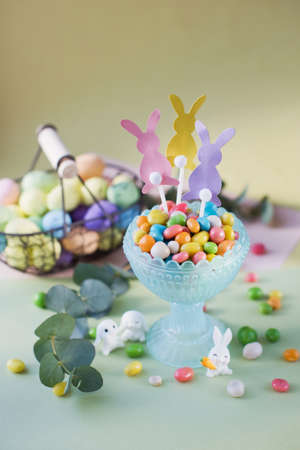 Pastel Easter decorations with bunny, colorful eggs candy on a light colorful backgroundの写真素材