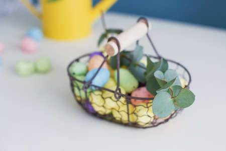Easter decorations with flowers and eggs. Beautiful flowers in yellow watering can and colorful eggs...