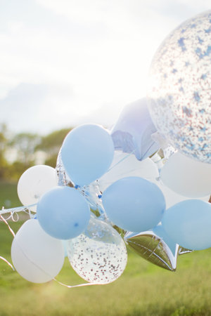 White and blue balloons with confetti. Birthday balloons outdoor at sunlight