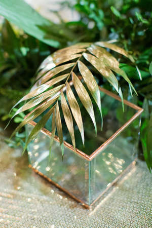 Golden palm tree leaves and glass vase, luxury tropic decoration