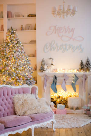 Christmas interior with fireplace, pink sofa, Christmas tree and pink and blue decorationsの写真素材