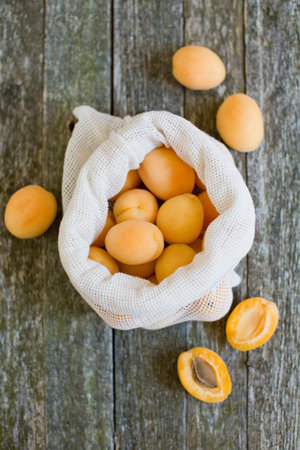 Ripe, fresh apricots in white eco bag on a vintage wooden backgroundの写真素材