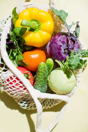 Eco string bag with fresh vegetables. Colorful veggies, pepper, tomatoes, cucumber, kohlrabi and...