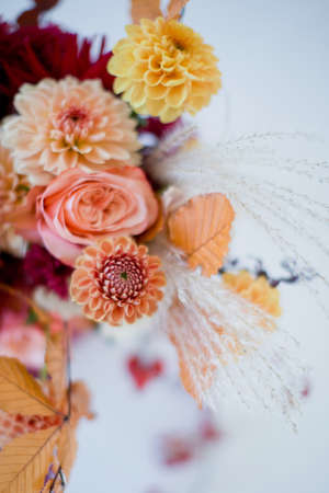 Beautiful autumn bouquet with orange and red flowers and berries. Autumn bouquet with ribbons on a white backgroundの写真素材