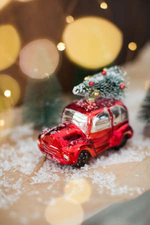 Small red car with Christmas tree. Christmas concept, holiday delivery. Christmas decorations and Christmas lightsの写真素材
