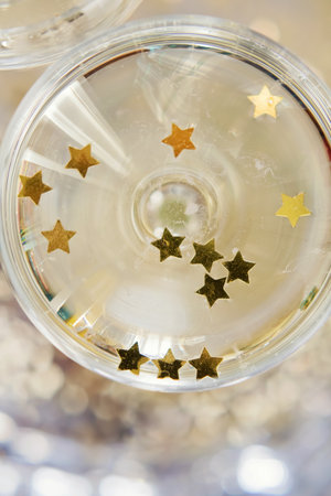 Glass of champagne with golden stars confetti on the silver tray. New year party conceptの写真素材