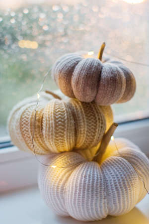 Knit handmade pumpkins and lights garland on the windowsill. Cozy fall autumn conceptの写真素材