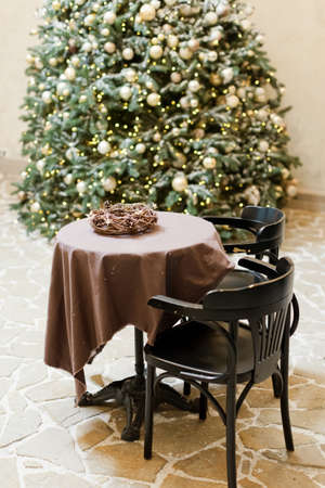 Table and chairs near Christmas tree. Christmas bakery showcase and Christmas decorations. Christmas tree with lights near city cafe with festive decorationsの写真素材