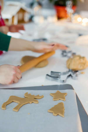Christmas baking background: dough, cookie cutters and Christmas decorations. Christmas cookies on a white table. Woman and girl making Christmas gingerbread cookiesの写真素材