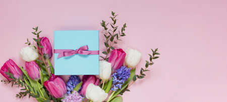 Beautiful bouquet and blue gift box with ribbon on a pink background. Holiday concept with copy space, place for text. 8 march, mothers day themeの写真素材