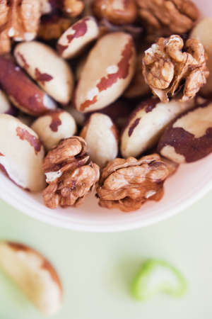 Mix of nuts in a pink bowl on a light green backgroundの写真素材