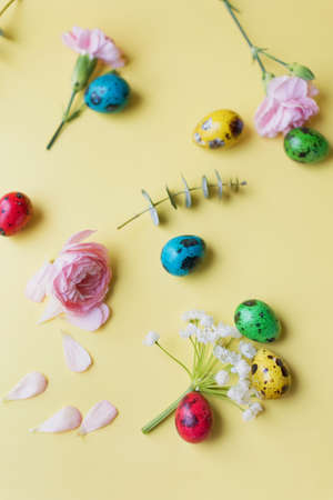 Easter eggs and flowers on a yellow background. Easter background with pastel colors details. spring holiday conceptの写真素材