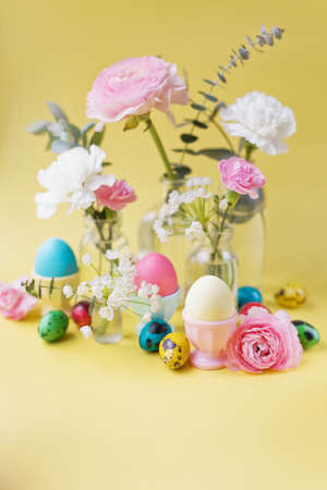 Easter eggs and flowers on a yellow background. Easter background with pastel colors details. spring holiday conceptの写真素材